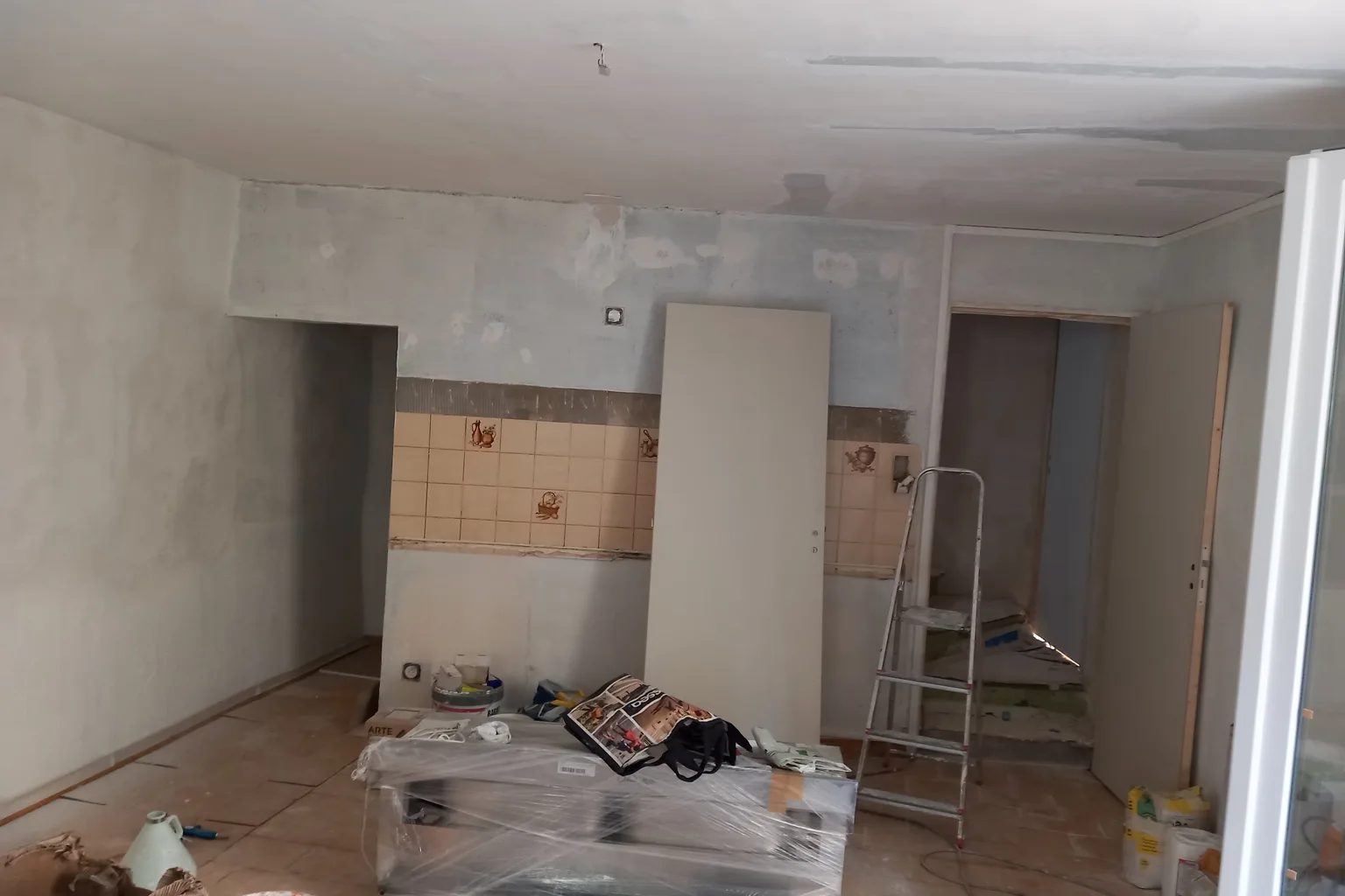 Chauffagiste professionnel réglant une chaudière murale à gaz moderne avec des tuyaux en cuivre apparents, dans une pièce technique équipée d’un ballon d’eau chaude et d’outils posés sur le plan de travail