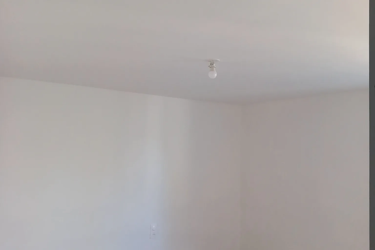 Plombier équipé en tenue de travail utilisant une ventouse pour déboucher un WC dans une salle de bain moderne, avec seau, trousse à outils et douche visible en arrière-plan